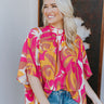 Front view of model wearing the Feeling Fine Top, which features a brown, pink, and orange swirl print, a high neckline, half-length sleeves, and a flowy fit. Shirt styled with front tuck
