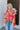 Front view of model wearing the Feeling Fine Top, which features a brown, pink, and orange swirl print, a high neckline, half-length sleeves, and a flowy fit. Shirt styled with front tuck