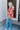 Full body side view of model wearing the Feeling Fine Top, which features a brown, pink, and orange swirl print, a high neckline, half-length sleeves, and a flowy fit.