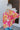 Back view of model wearing the Feeling Fine Top, which features a brown, pink, and orange swirl print, a high neckline, half-length sleeves, and a flowy fit.