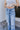 Close-up upper front view of model wearing the Ceros: Charlotte Dad Jeans, which feature medium-wash-denim with light distressing, a straight let fit, and front and back pockets