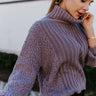 Detail view of the Days Go By Sweater in Grey that features grey cable knit fabric on the front, loose turtleneck, popcorn detailing on the back and sleeves and long sleeves with cable knit wrists.