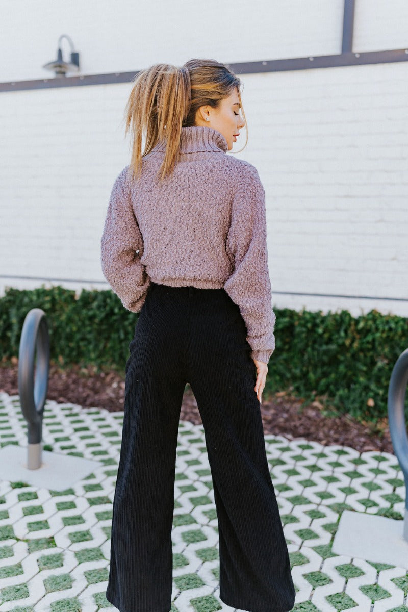 Back view of the Days Go By Sweater in Grey that features grey cable knit fabric on the front, loose turtleneck, popcorn detailing on the back and sleeves and long sleeves with cable knit wrists.