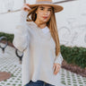 Front view of the Stand Out Sweater in Grey that features grey ribbed knit fabric, v neckline with fringe details, collar attached, dropped shoulders and long balloon sleeves with cable knit wrists.