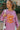 Front view of model wearing the More Self Love Sweatshirt, which has a purple colored material, a round neckline with a ribbed trim, a long sleeve, a purple and orange graphic front reading "More Self Love", and side slits