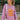 Front view of model wearing the More Self Love Sweatshirt, which has a purple colored material, a round neckline with a ribbed trim, a long sleeve, a purple and orange graphic front reading "More Self Love", and side slits