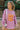 Front view of model wearing the More Self Love Sweatshirt, which has a purple colored material, a round neckline with a ribbed trim, a long sleeve, a purple and orange graphic front reading "More Self Love", and side slits