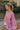 Side view of model wearing the More Self Love Sweatshirt, which has a purple colored material, a round neckline with a ribbed trim, a long sleeve, a purple and orange graphic front reading "More Self Love", and side slits