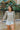 Front view of model wearing the Forever Yours Top, which has a sage green fabric , a round neckline, long sleeves, a back tie closure at the neck, and a flowy fit