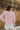 Back view of the Cruel Summer Top that features a pink colored material, a white gingham print, a V neckline, a long ruched sleeve with adjustable ties, and a flowy fit.