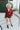 Full body front view of model wearing the Sloane Corduroy Shacket in Wine, which features a maroon corduroy material, a collar neckline, a button-up front, a front pocket, and long cuffed sleeves. Worn over white top.