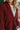 Close-up front view of model wearing the Sloane Corduroy Shacket in Wine, which features a maroon corduroy material, a collar neckline, a button-up front, a front pocket, and long cuffed sleeves. Worn over white top.