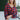Front view of model wearing the Good Life Plaid Top, which has a red material with a navy plaid print, a scoop neckline, a notched neckline with an adjustable tie, a long sleeve, and a flowy fit.