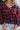 Close-up front view of model wearing the Good Life Plaid Top, which has a red material with a navy plaid print, a scoop neckline, a notched neckline with an adjustable tie, a long sleeve, and a flowy fit.