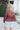 Back view of model wearing the Good Life Plaid Top, which has a red material with a navy plaid print, a scoop neckline, a notched neckline with an adjustable tie, a long sleeve, and a flowy fit.