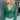 Front view of model wearing the Follow Your Heart Top, which features a green colored material, a V surplice neckline, a long sleeve, a knot detail at the waist, and a tiered ruffle bottom