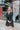 Front view of model wearing the Lost In The Moment Dress in Black, which has a black satin material, a collar neck, a surplice V neckline with a clasp closure, a long cuffed sleeve, a knot detail at the waist, and a midi length.