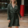 Front view of model wearing the Lost In The Moment Dress in Green, which features a forest green satin material, a collar neck, a surplice V neckline with a clasp closure, long cuffed sleeves, a knot detail at the waist, and a midi length.