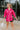 Frontal view of the Stolen Dreams Top that features a hot pink material, a collar neck and button-up front, pleated 3/4 sleeves with a bow at the wrist, and a curved bottom hem with side slits.