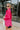 Side view of the Stolen Dreams Top that features a hot pink material, a collar neck and button-up front, pleated 3/4 sleeves with a bow at the wrist, and a curved bottom hem with side slits.