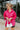 Frontal view of the Stolen Dreams Top that features a hot pink material, a collar neck and button-up front, pleated 3/4 sleeves with a bow at the wrist, and a curved bottom hem with side slits.