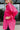 Side view of the Stolen Dreams Top that features a hot pink material, a collar neck and button-up front, pleated 3/4 sleeves with a bow at the wrist, and a curved bottom hem with side slits.