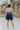 Back view of the Light of Your Life Mini Dress that features a tulle material, a monochromatic tiered design, a straight neckline, a sleeveless design with thin adjustable straps, a back zipper closure, and a mini length.