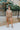 Full body front view of model wearing the Let's Go Top, which features a round neckline, a long sleeve, a raw curved bottom hem, and a flowy fit. Worn untucked with matching shorts.