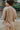 Back view of model wearing the Let's Go Top, which features a round neckline, a long sleeve, a raw curved bottom hem, and a flowy fit. Worn untucked with matching shorts.