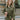 Front view of model wearing the Road Trip Romper In Olive, which has an olive green material, a collar neck, a button-up front, two front pocket, long sleeves and a tie belt at the waist.