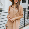 Front view of model wearing the Never Better Dress, which features a camel colored material, a faux leather collar neckline, a faux leather button-up front, short sleeves, a faux leather front pocket, and a mini length.