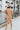 Full body back view of model wearing the Never Better Dress, which features a camel colored material, a faux leather collar neckline, a faux leather button-up front, short sleeves, a faux leather front pocket, and a mini length.