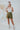 Frontal view of the Livin' The Dream Shorts that features an olive green colored material, a high-rise fit, an elastic waist, a belt detail, side pockets, and a flowy fit.