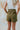 Back view of the Livin' The Dream Shorts that features an olive green colored material, a high-rise fit, an elastic waist, a belt detail, side pockets, and a flowy fit.