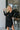 Frontal view of the Slipped Away that features a black colored knit material, a surplice neckline, a long sleeve, ruched side detailing with adjustable strings, a side slit, a mini length, and a tight fit.