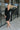 Frontal view of the Slipped Away that features a black colored knit material, a surplice neckline, a long sleeve, ruched side detailing with adjustable strings, a side slit, a mini length, and a tight fit.