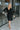 Frontal view of the Slipped Away that features a black colored knit material, a surplice neckline, a long sleeve, ruched side detailing with adjustable strings, a side slit, a mini length, and a tight fit.