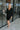 Frontal view of the Slipped Away that features a black colored knit material, a surplice neckline, a long sleeve, ruched side detailing with adjustable strings, a side slit, a mini length, and a tight fit.