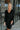 Frontal view of the Slipped Away that features a black colored knit material, a surplice neckline, a long sleeve, ruched side detailing with adjustable strings, a side slit, a mini length, and a tight fit.