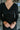 Frontal view of the Slipped Away that features a black colored knit material, a surplice neckline, a long sleeve, ruched side detailing with adjustable strings, a side slit, a mini length, and a tight fit.