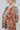 Frontal view of the Can't Stop Me Flannel Jacket that features a rust colored flannel material, a multi-colored plaid pattern, a brown thermal material hood with adjustable strings, a button-up front, long cuffed sleeves, a brown thermal material siding, 