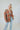Frontal view of the Can't Stop Me Flannel Jacket that features a rust colored flannel material, a multi-colored plaid pattern, a brown thermal material hood with adjustable strings, a button-up front, long cuffed sleeves, a brown thermal material siding, 