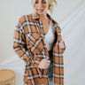 Frontal view of the In The Air Flannel Top that features a camel colored flannel material, a navy and white plaid pattern, a collar neck, a button-up front, two front pockets, a long cuffed sleeve, side slits, a high-low design, and an oversized fit.