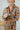 Frontal view of the In The Air Flannel Top that features a camel colored flannel material, a navy and white plaid pattern, a collar neck, a button-up front, two front pockets, a long cuffed sleeve, side slits, a high-low design, and an oversized fit.