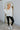 Full body front view of model wearing the What A Stud Hoodie, that features an ivory ribbed material, a hood, a 3/4 button-up front,  long sleeves, stud detailing at the shoulders and back, and a raw edge bottom hem.