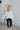 Full body front view of model wearing the What A Stud Hoodie, that features an ivory ribbed material, a hood, a 3/4 button-up front,  long sleeves, stud detailing at the shoulders and back, and a raw edge bottom hem.