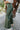 Close-up side view of model wearing the Make You Mine Pants, which feature a hunter green faux-leather material, a pleated design, an elastic waist, and a wide leg fit.