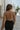Back view of the Spell On You Top that features a brown textured material, a collar neck, long sleeves, a surplice front with an adjustable tie detail, and lettuce edge hems.