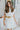 Frontal view of the Heart Breaker Sweater Dress that features an ivory knit material, a turtleneck, a sleeveless design, and a mini length. Dress is belted.