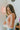 Side view of model wearing the Taking Chances Top, which features a blush colored ribbed material, a collar neck, a V neckline, a long sleeve, and a cropped fit.